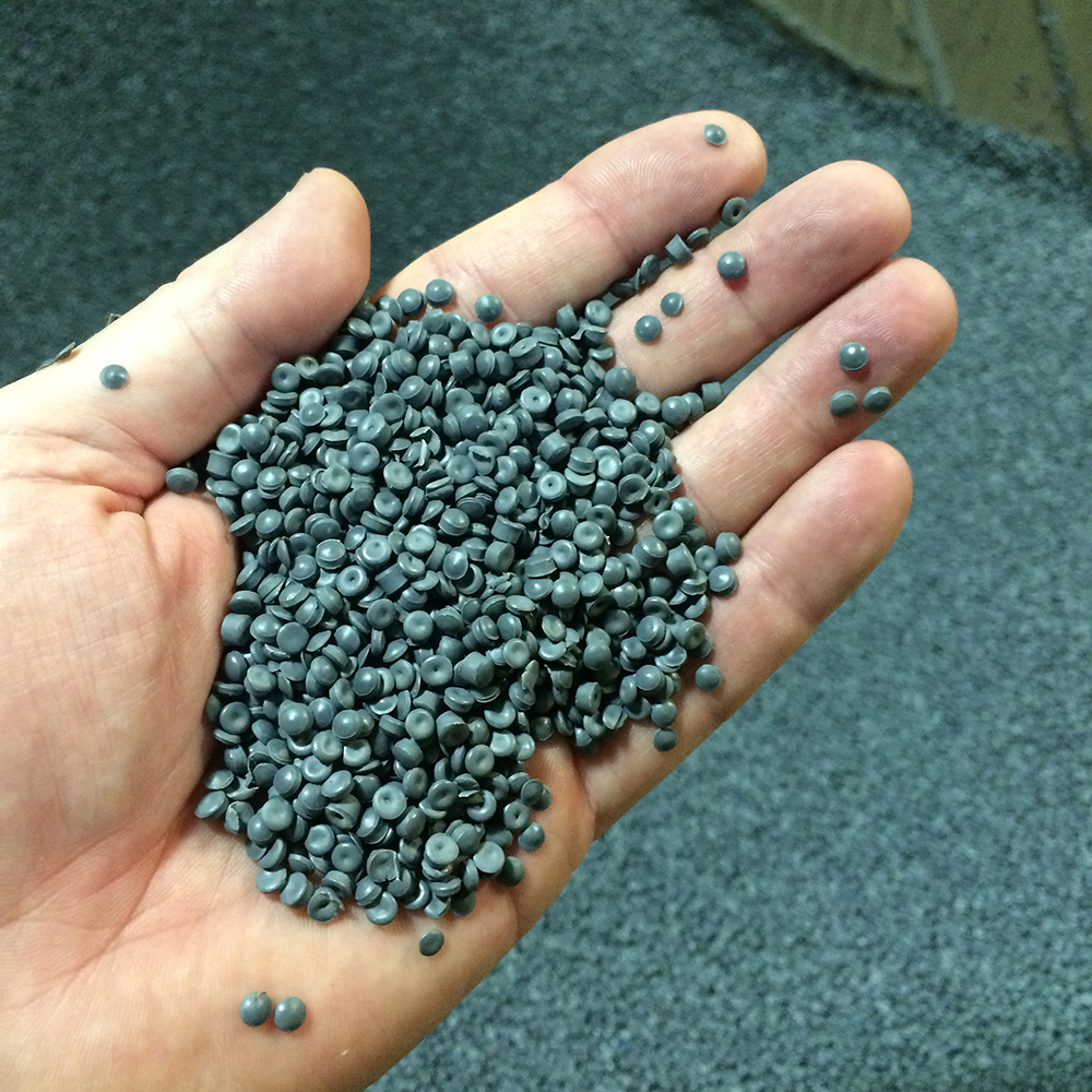 Hand holding grey post consumer recycled plastic pellets